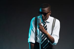 Retro african american jazz singer with microphone. Wearing shirt and tie and sunglasses. Studio shot.
